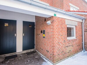 Ein Gebäude mit zwei dunkel gefärbten Türen, einer Ziegelwand und einem Fenster.