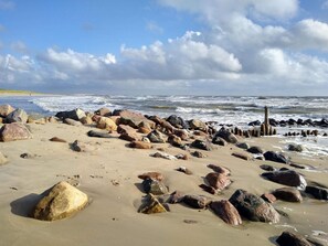 A beach with large rocks and a wooden structure. - Cozy Holiday Home in BlÃ¥vand near Beach (Blavand)