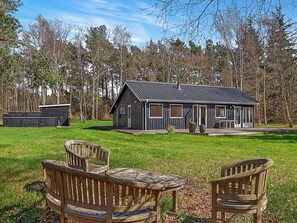 A cabin with a deck, surrounded by a grassy area and trees.