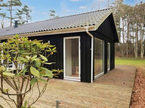 A black building with a tiled roof, a glass door, and a wooden deck.