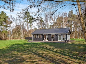 A cabin with a dark roof, large windows, and a porch area.