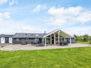 A building with a covered patio area, outdoor seating, and a grassy lawn. - 5 Star Holiday Home in Albaek (Aalbaek)