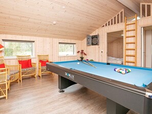 A pool table with a dartboard and billiard cues, wicker chairs with red cushions, and a wooden ceiling. - 8 Person Holiday Home in Albaek (Aalbaek)