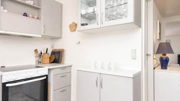 Una cocina con armarios blancos, horno empotrado y encimera con utensilios de cocina.