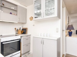 A kitchen with white cabinetry, a built-in oven, and a countertop with kitchen utensils. - Spacious Holiday Home in Borkop near Beach (Borkop)