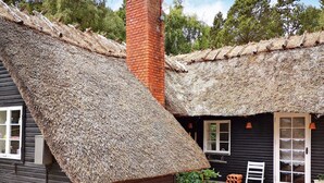 A traditional wooden house with a thatched roof and a brick chimney. - 6 Person Holiday Home in Rodby (Rodby)