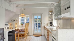 A kitchen with a dining area, wooden furniture, a stove, and a window with a view. - 6 Person Holiday Home in Rodby (Rodby)