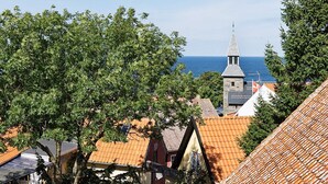 A coastal town with traditional architecture, including a church with a pointed steeple and terracotta-tiled roofs. - Quaint Holiday Home in Løkken With Beach Nearby (Gudhjem)