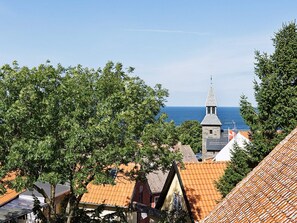 A coastal town with traditional architecture, including a church with a pointed steeple and terracotta-tiled roofs. - Quaint Holiday Home in LÃ¸kken With Beach Nearby (Gudhjem)