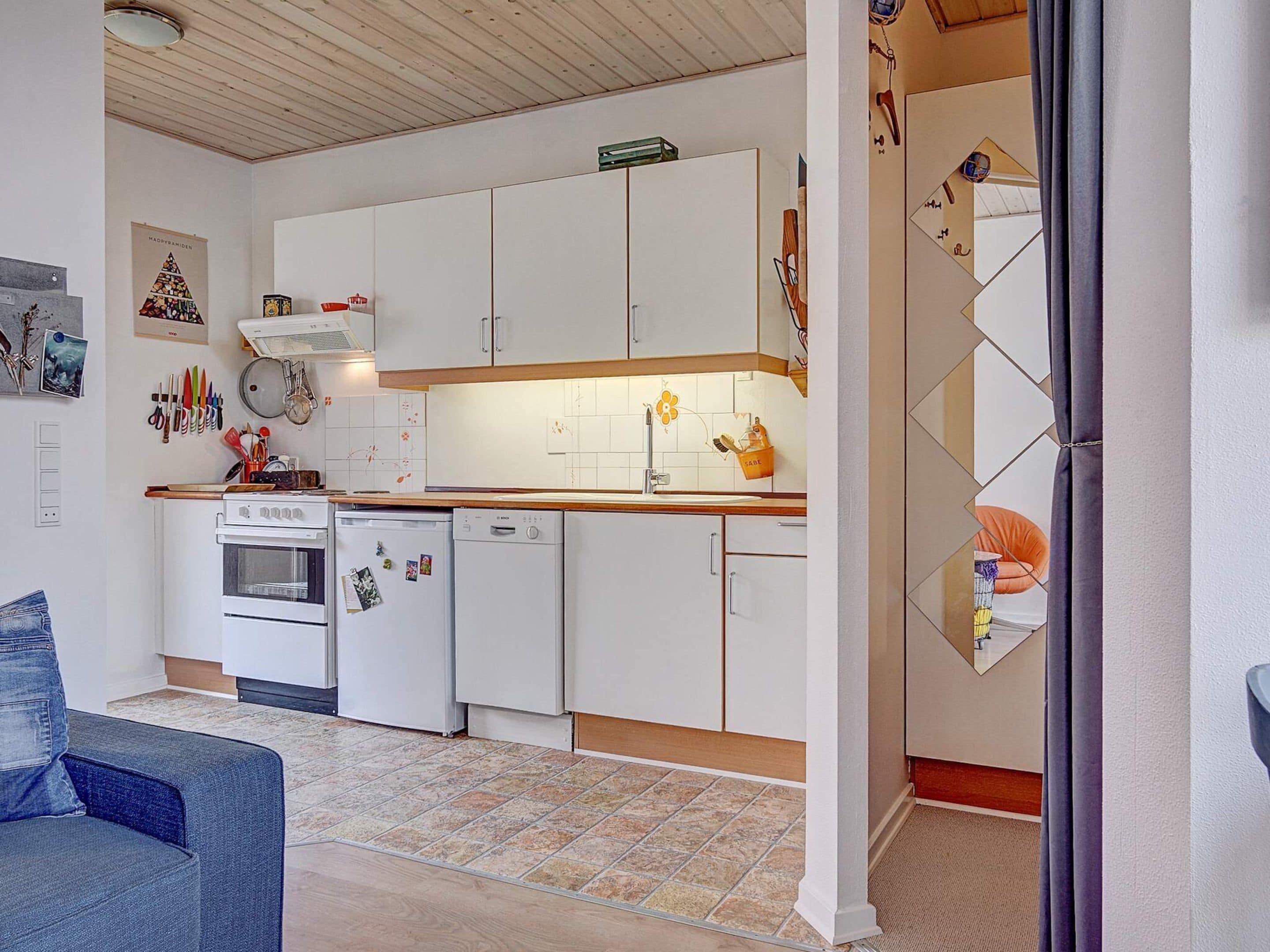 Una cocina pequeña con gabinetes blancos, estufa y lavavajillas.