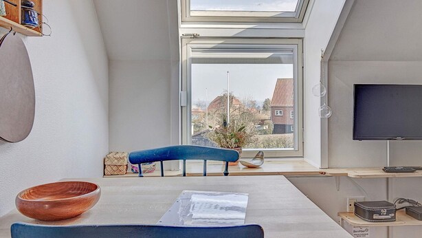 A modern room with a skylight, a television, a dining table, and a blue chair. - Quaint Holiday Home in LÃ¸kken With Beach Nearby (Gudhjem)