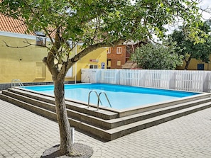 A rectangular swimming pool with steps leading into it, surrounded by a white fence, and a tree in the foreground. - Quaint Holiday Home in LÃ¸kken With Beach Nearby (Gudhjem)