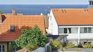 A coastal residential area with terracotta-tiled roofs, a white building with a balcony, and a clear view of the sea. - Quaint Holiday Home in LÃ¸kken With Beach Nearby (Gudhjem)