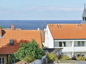 A coastal residential area with terracotta-tiled roofs, a white building with a balcony, and a clear view of the sea. - Quaint Holiday Home in LÃ¸kken With Beach Nearby (Gudhjem)
