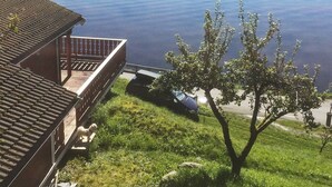 A house with a balcony overlooking a lake. - 8 Person Holiday Home in Etne (Etne)