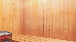 Un sauna avec des murs en bois et un banc.
