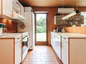 Una cocina moderna con armarios blancos, horno empotrado y un amplio ventanal.