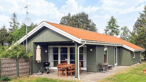 Une maison de plain-pied dotée d’un patio couvert, d’un barbecue et d’une table à manger avec des chaises.