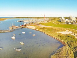 A marina with boats docked, a pier, and a construction crane in the background.