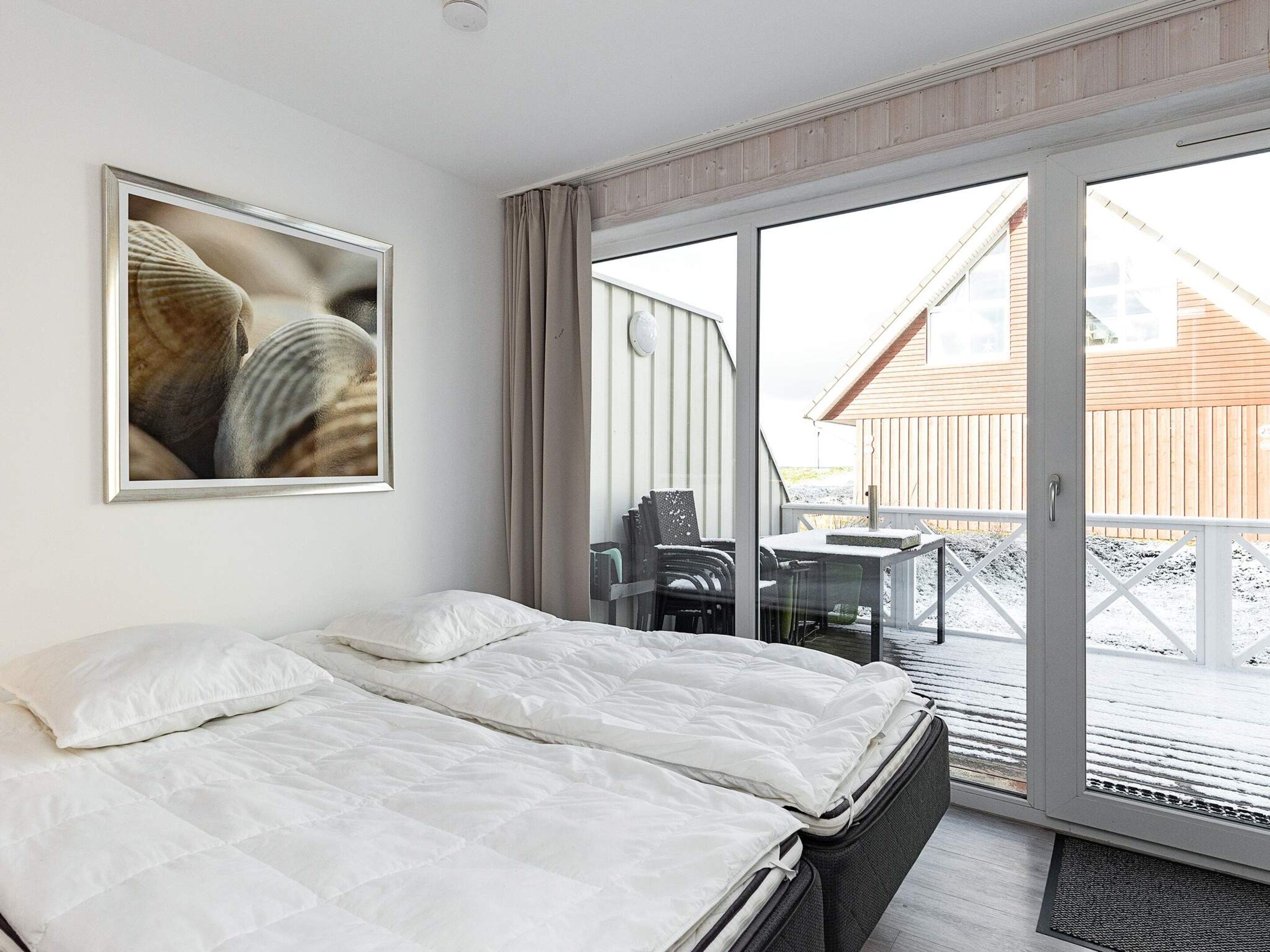 Habitación de hotel con una cama, un cuadro en la pared y vistas al exterior.