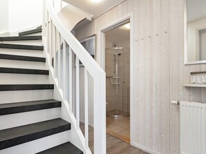 A staircase leading to a shower area with a wooden wall and a white door. - Holiday Home in Wendtorf (Wendtorf)