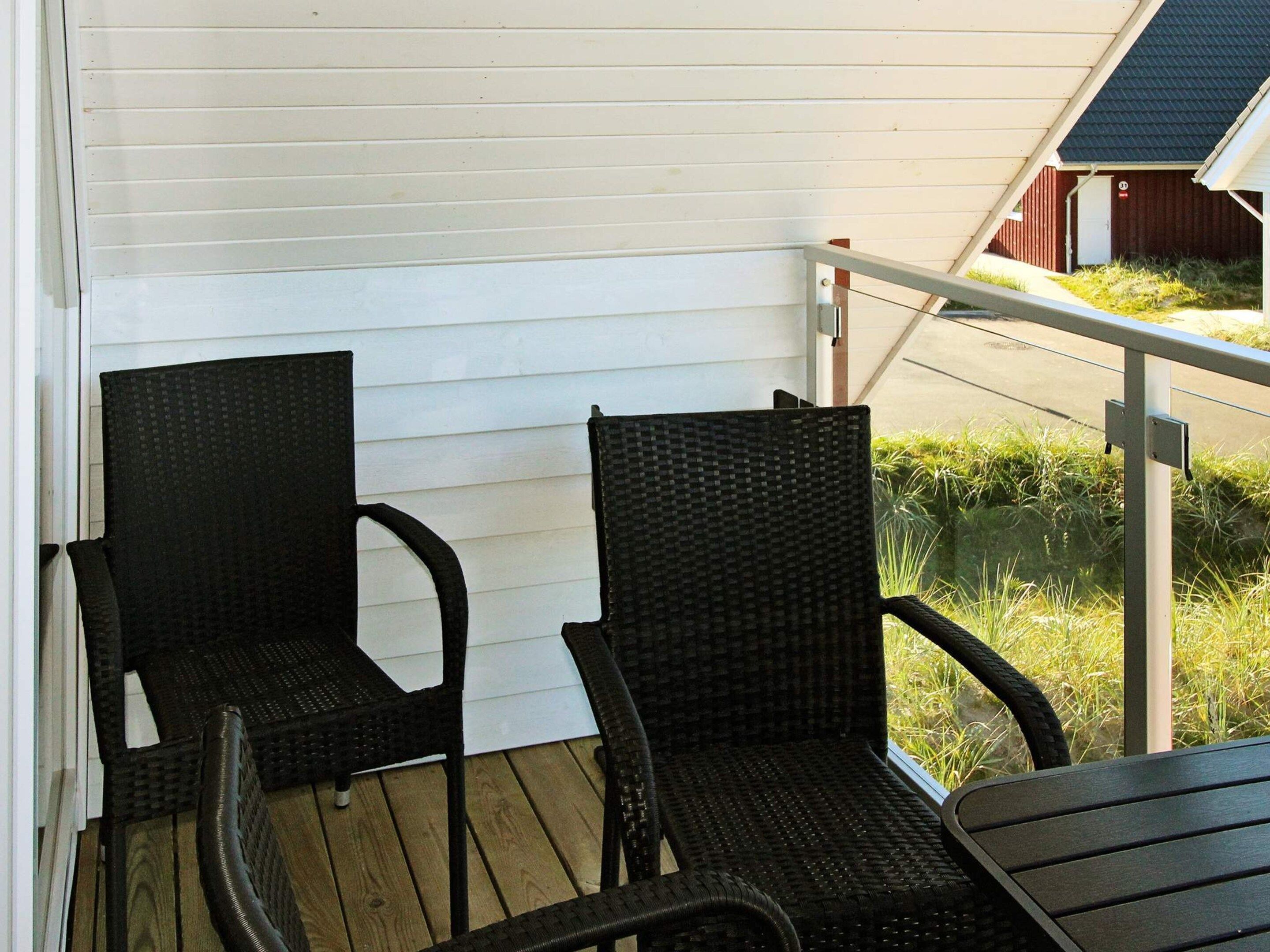 A covered outdoor seating area with two chairs and a table.