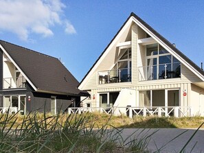 A two-story building with a sloped roof, large windows, and a white fence in front. - Holiday Home in Wendtorf (Wendtorf)