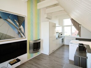 A modern kitchen with white cabinets, a built-in oven, and a window with curtains. - Holiday Home in Wendtorf (Wendtorf)