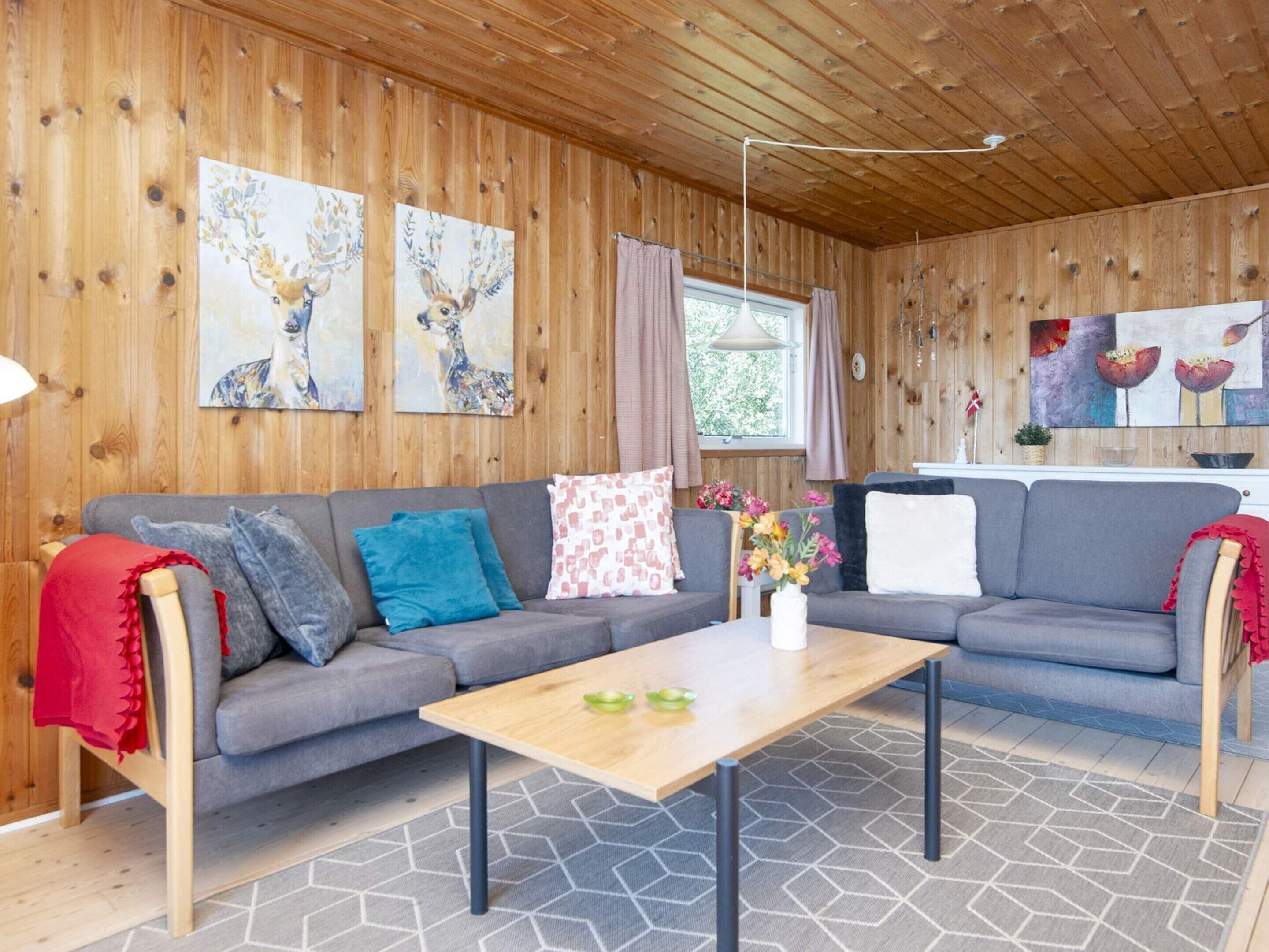 A cozy living room with a grey sofa, a wooden coffee table, and artwork on the walls.