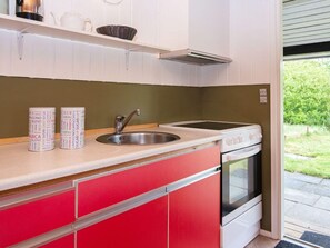 A compact kitchen with a sink, stove, and a red cabinet.