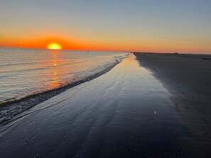 A beach with a sunset, calm water, and a clear sky.