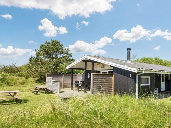 A small cabin with a covered porch, a picnic table, and a chimney.
