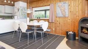 Una habitación acogedora con techo de madera, una mesa de comedor con sillas, un mapa en la pared y una chimenea.