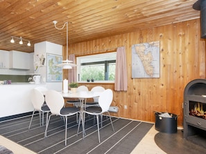 Ein gemütliches Zimmer mit Holzbalkendecke, einem Esstisch mit Stühlen, einer Karte an der Wand und einem Kamin.