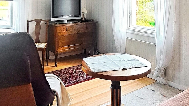 A living room with a round table, a television on a wooden cabinet, and a window with curtains. - 6 Person Holiday Home in Vara (Vara)