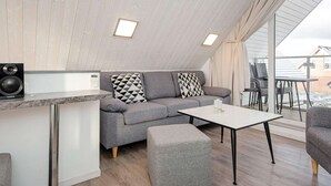 A modern loft-style room with a sofa, ottoman, and a small table. - Holiday Home in Wendtorf (Wendtorf)