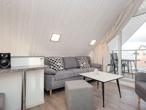 Une chambre moderne de style loft, comprenant un canapé, un pouf et une petite table.
