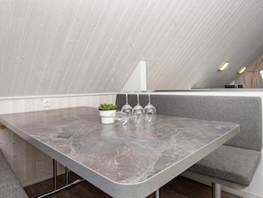 A modern kitchen with a marble countertop, a small potted plant, and wine glasses.