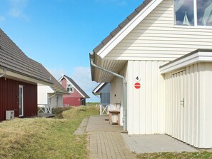 Une rangée de bâtiments d’un seul étage, avec un chemin menant à une entrée fermée par un portail.