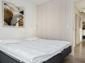A bedroom with a bed, a wall-mounted light, and a framed picture. - Holiday Home in Wendtorf (Wendtorf)