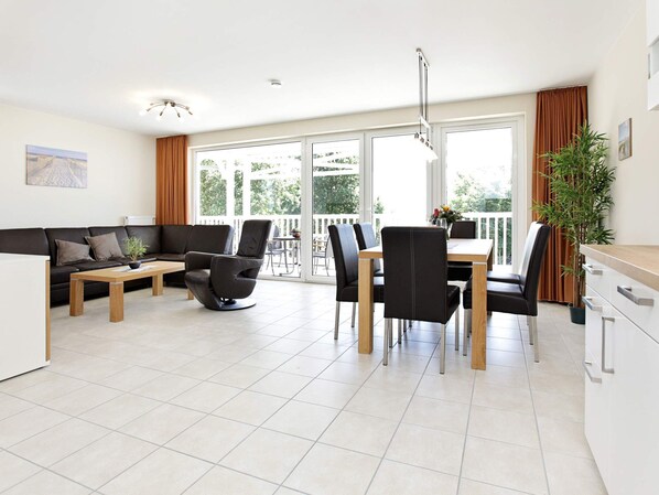 Una sala de estar moderna con un sofá, una mesa de comedor con sillas y una zona de cocina.