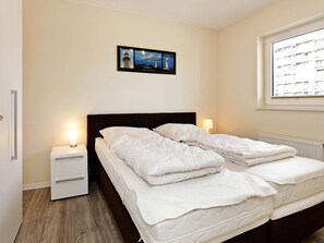Un dormitorio con cama, mesitas de noche, una ventana con vistas y un cuadro en la pared.