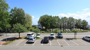 Un parking avec plusieurs voitures, des arbres et un ciel dégagé.