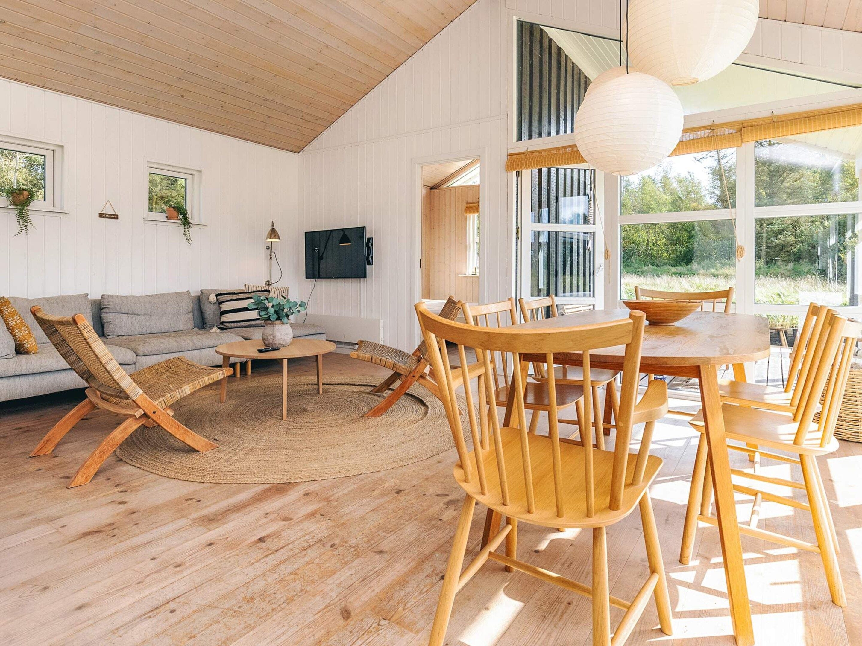 A spacious living area with a wooden floor, a sofa, a coffee table, and a dining table with chairs.