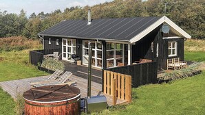 A modern house with a large deck, a wooden barrel, and a glass-enclosed porch. - 4 Star Holiday Home in Oster Assels (Ă˜ster Assels)