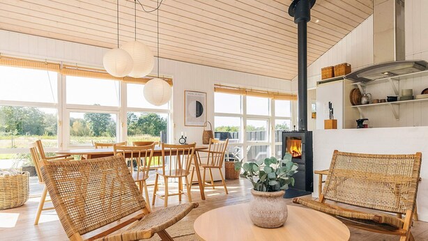 A cozy living room with wicker furniture, a round wooden table, and a fireplace. - 4 Star Holiday Home in Oster Assels (Ă˜ster Assels)