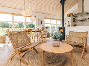 Una sala de estar acogedora con muebles de mimbre, una mesa redonda de madera y una chimenea.