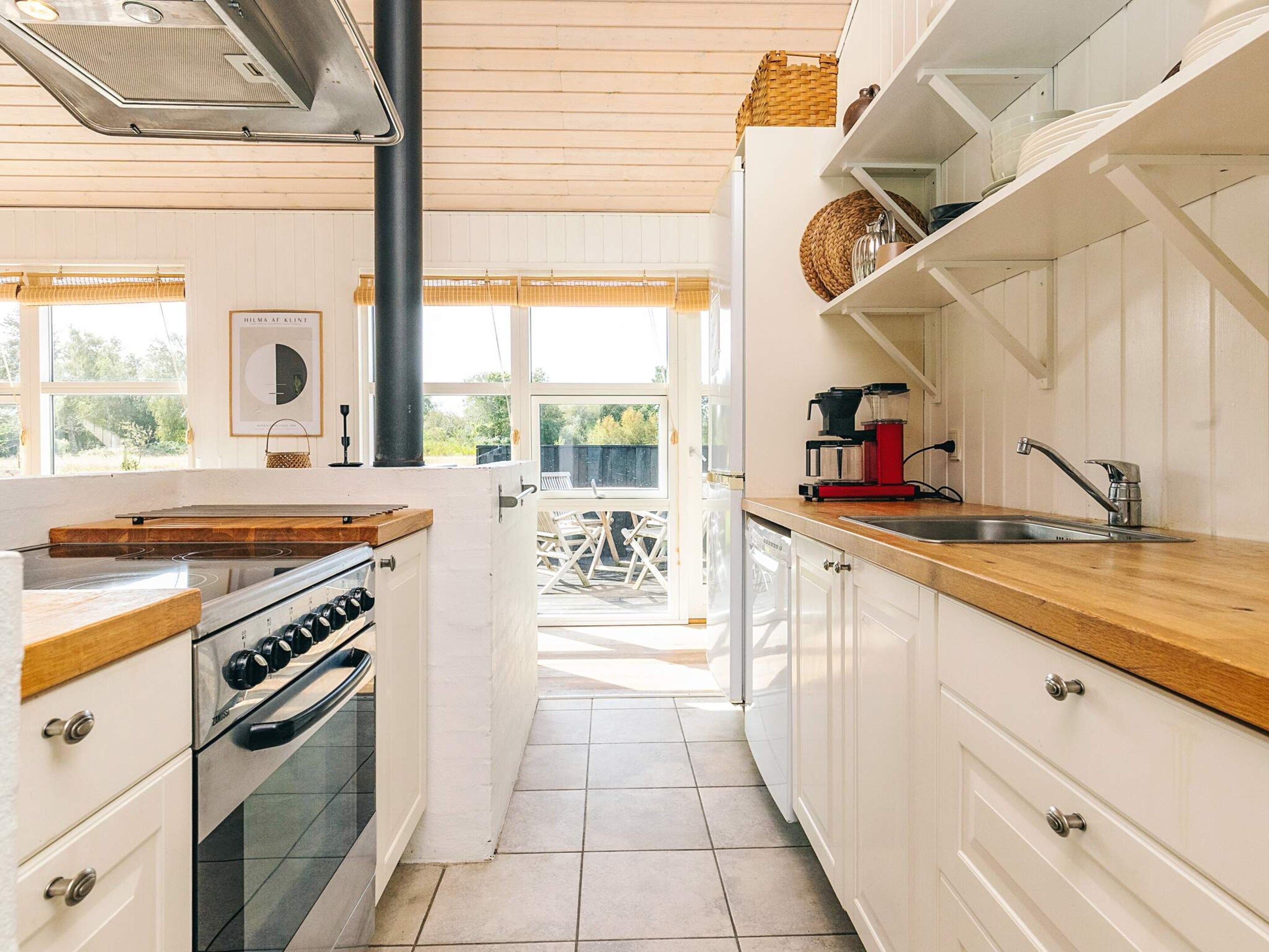 Una cocina con armarios blancos, encimera de madera, estufa y cafetera.