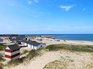 A coastal area with a sandy beach, several small boats, and a few buildings with blue and white exteriors. - Modish Holiday Home in Jutland near Beach (Thisted)