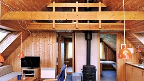 Ein gemütliches Dachzimmer mit Schlafkoje, Fernseher, Kamin und Essecke.